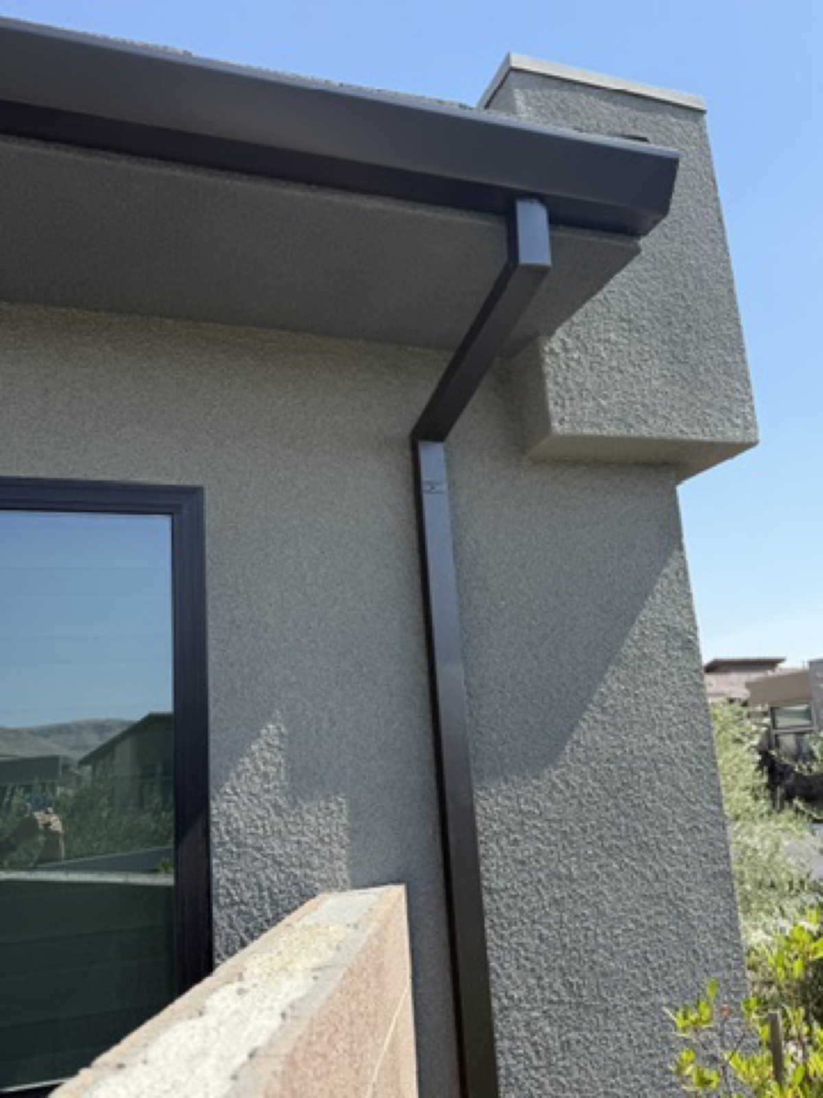 City Seamless straight-face gutter with downspout routing on a modern roofline.