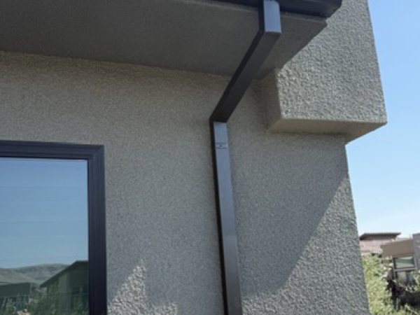 City Seamless straight-face gutter with downspout routing on a modern roofline.